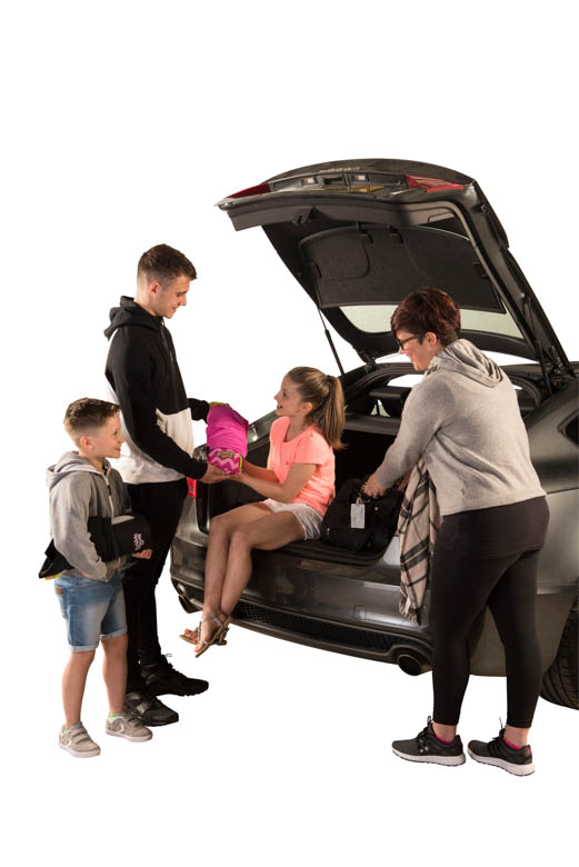 Family at boot of car placing seat in girls hands - pink seat 2 Family at boot of car placing seat in girls hands - pink seat 2